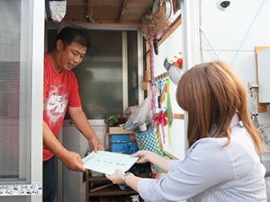 仮設住宅に発行物を届ける様子