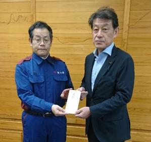 熊本県東京事務所長に目録を手渡す佐藤雅裕副議長の写真